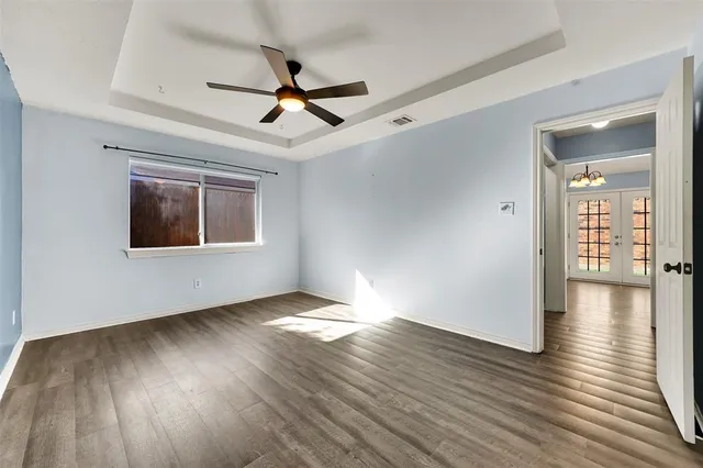 a view of a big room with wooden floor a ceiling fan and windows