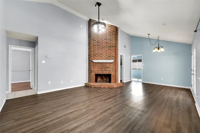 a view of a room with wooden floor fireplace and windows