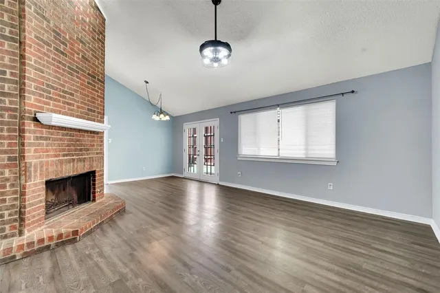 a view of an empty room with wooden floor fireplace and a window