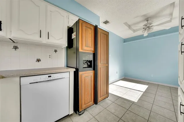 a view of a refrigerator in kitchen and white cabinets