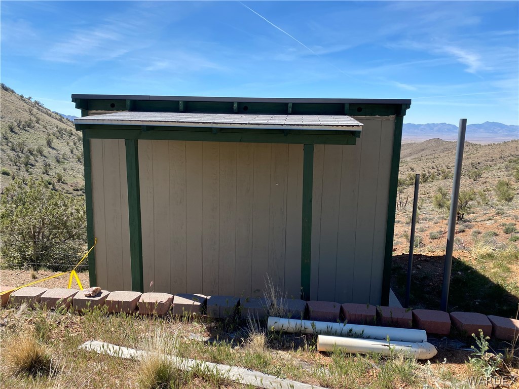 9095 Elliott Ridge Road Kingman, AZ 86401 - Photo 46 of 54 The property features a utility shed with a shingled roof and wood siding