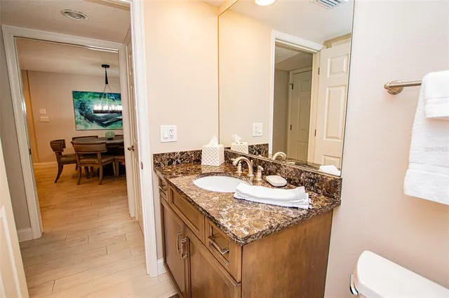 a bathroom with a granite countertop sink a toilet and a mirror
