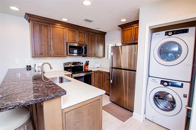 a kitchen with granite countertop a refrigerator and a stove top oven