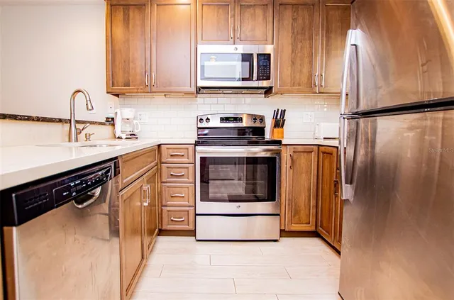a kitchen with stainless steel appliances granite countertop a stove a sink and a refrigerator
