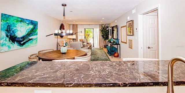 a view of a kitchen with kitchen island stainless steel appliances refrigerator dining table and chairs