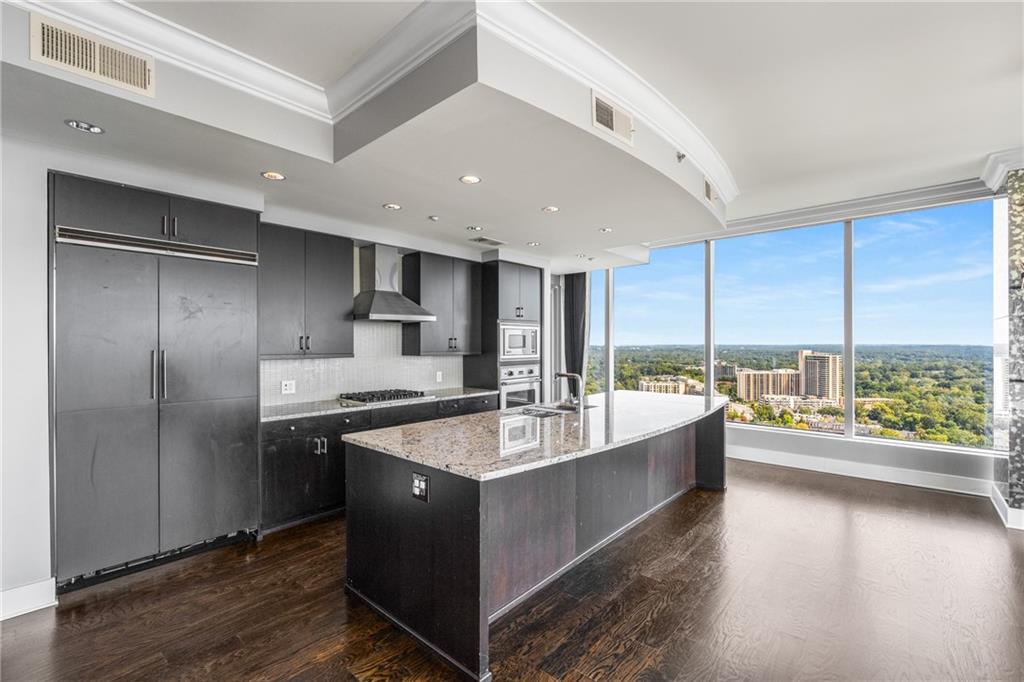 3630 Peachtree Road Northeast, Unit 2404 Atlanta, GA 30326 - Photo 10 of 48 a large kitchen with a large counter top stainless steel appliances and wooden floor
