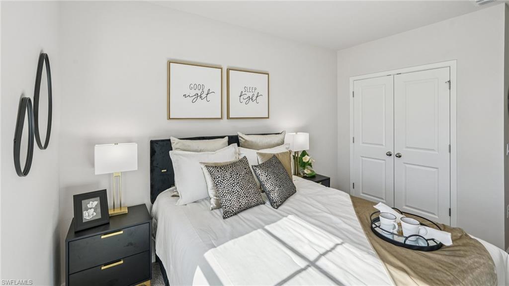 17584 Shade Tree Loop Punta Gorda, FL 33982 - Photo 14 of 35 Bedroom with light-toned walls, a dark upholstered headboard, and dual panel closet doors