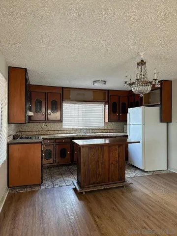 a kitchen with stainless steel appliances granite countertop a stove a sink dishwasher and a refrigerator with wooden floor