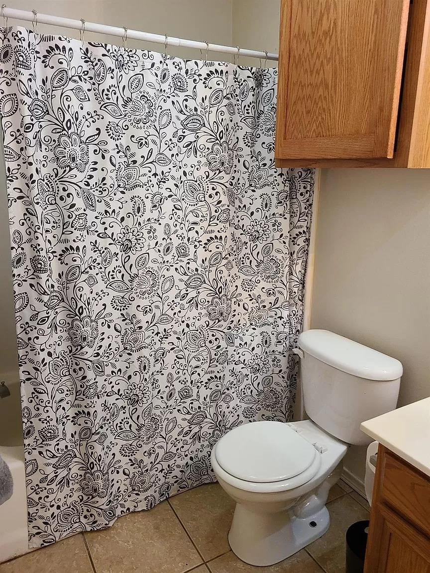 304 North Clinton Avenue, Unit A Lubbock, TX 79416 - Photo 8 of 24 a white toilet sitting next to a shower curtain