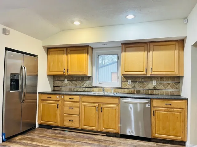a kitchen with granite countertop a sink a stove cabinets and stainless steel appliances