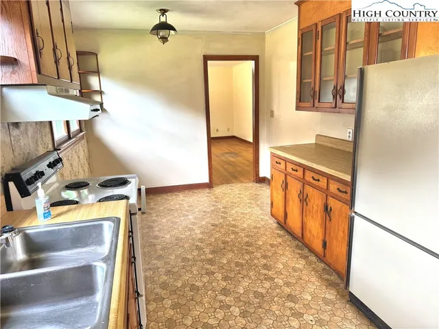 a view of a kitchen with fridge and wooden floor