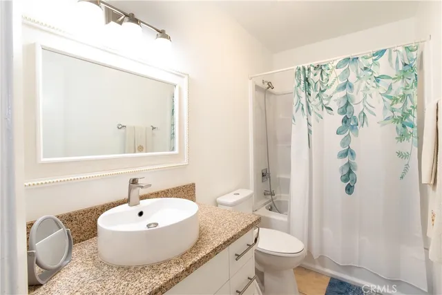 a bathroom with a granite countertop sink toilet a mirror and shower