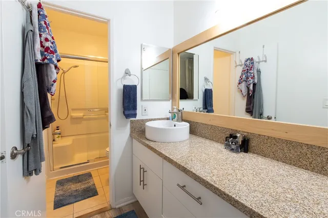 a bathroom with a granite countertop shower sink and mirror