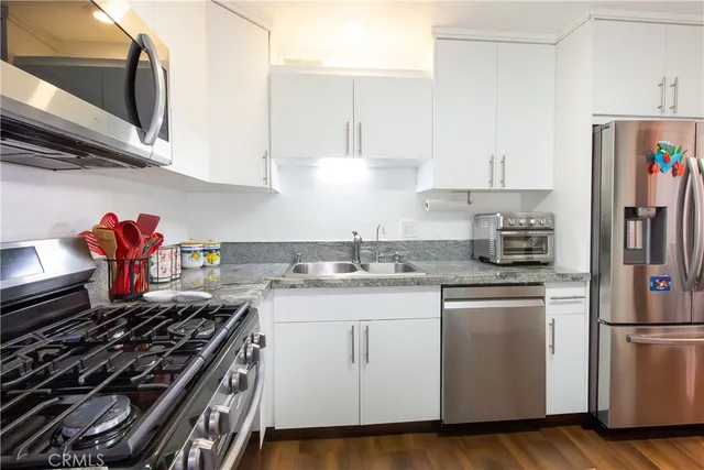a kitchen with granite countertop a sink stove and white cabinets