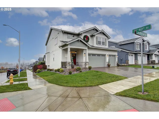 a view of a white house next to a yard with big trees
