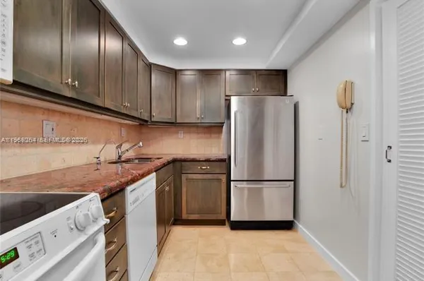 a kitchen with stainless steel appliances granite countertop a refrigerator a sink dishwasher a stove and a refrigerator with wooden floor