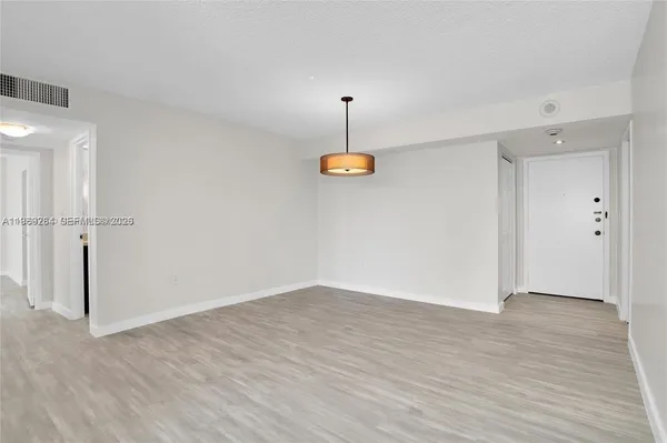 an empty room with wooden floor door and windows