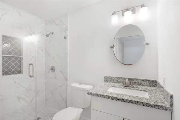 a bathroom with a granite countertop sink a toilet and a mirror