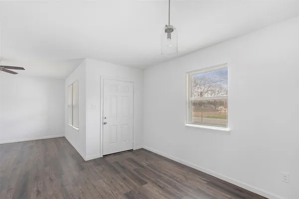 an empty room with wooden floor chandelier fan and windows