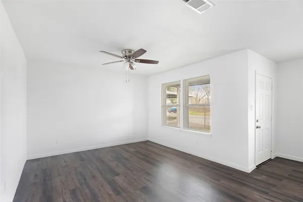 a view of a livingroom with a kitchen island wooden floor and a ceiling fan