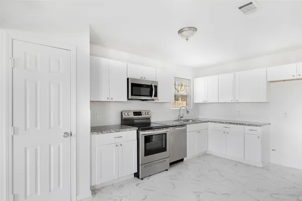 a kitchen with white cabinets stainless steel appliances and sink