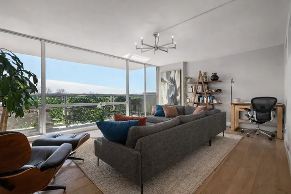 a living room with furniture a ceiling fan and a large window