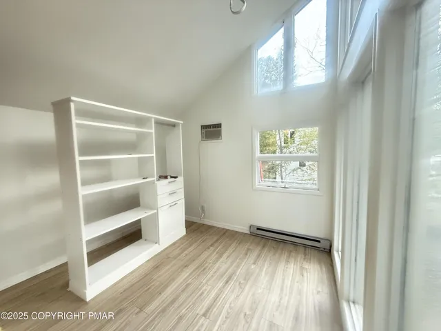 a view of an empty room with a window and wooden floor