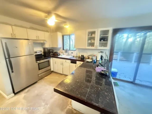 a kitchen with stainless steel appliances granite countertop a refrigerator a sink a stove top oven a washer and dryer