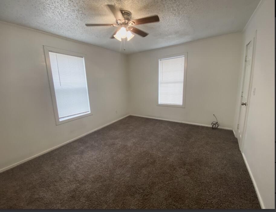 2114 27th Street Lubbock, TX 79411 - Photo 5 of 9 a view of a big room with windows and chandelier fan