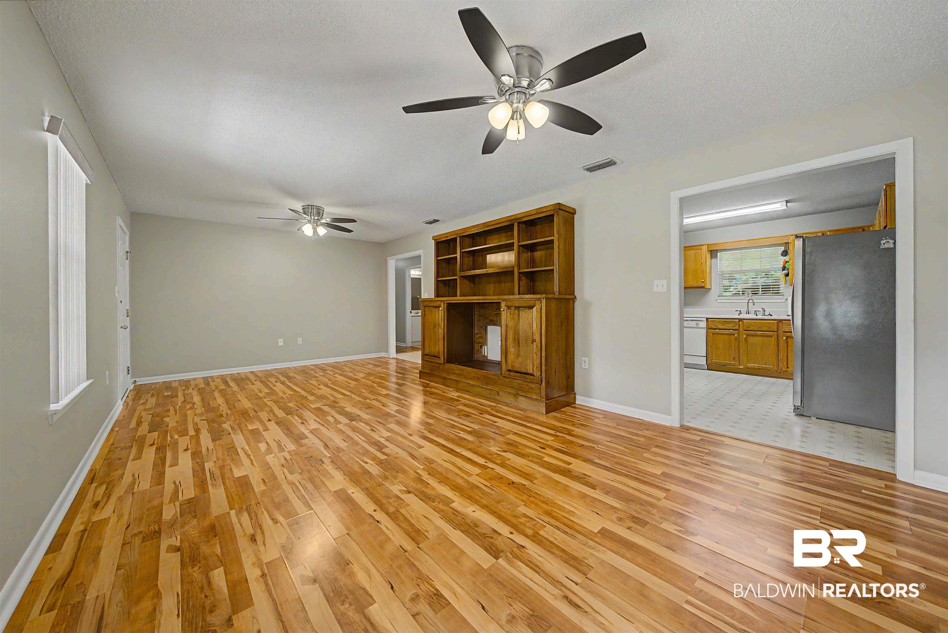 22963 Highway 98 Foley, AL 36535 - Photo 8 of 52 Spacious living area featuring wood-finish flooring, light gray walls, and multiple ceiling fans