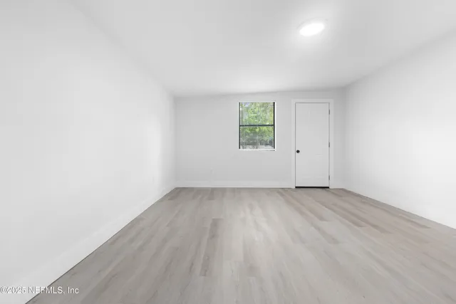 an empty room with wooden floor and window