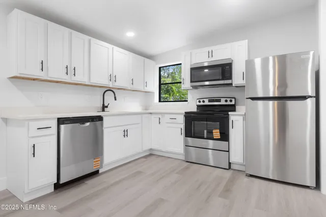 a kitchen with white cabinets and stainless steel appliances