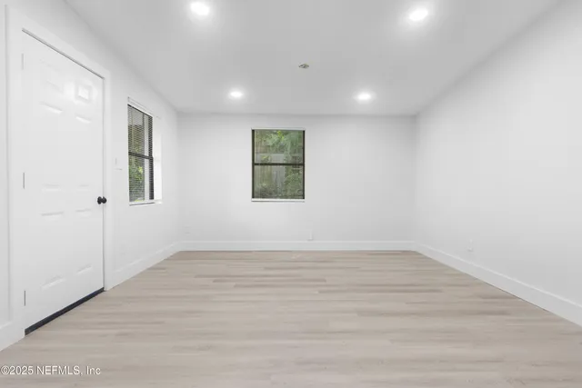 an empty room with wooden floor and windows