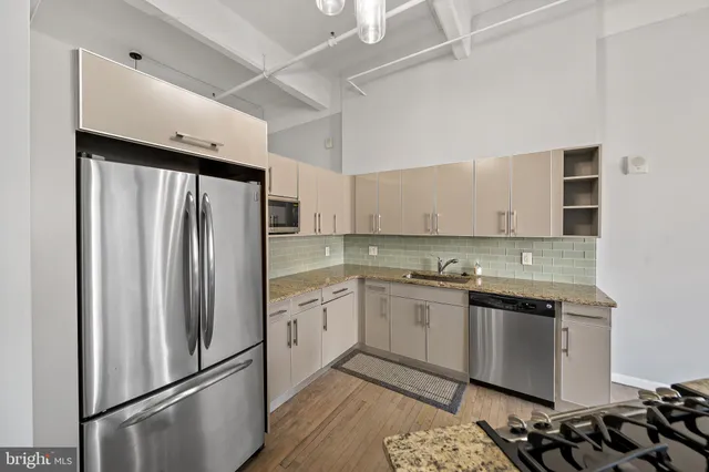 a kitchen with stainless steel appliances granite countertop a refrigerator a sink and white cabinets