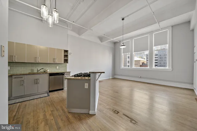 a kitchen with granite countertop a stove a sink and white cabinets with wooden floor