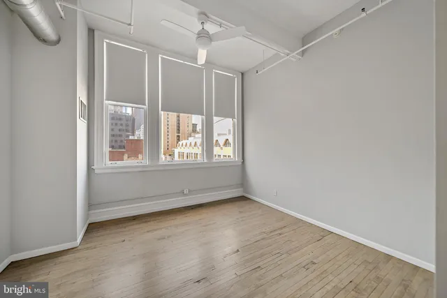 an empty room with wooden floor and windows