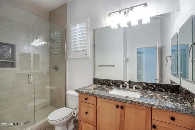 a bathroom with a granite countertop sink toilet a mirror a vanity and shower