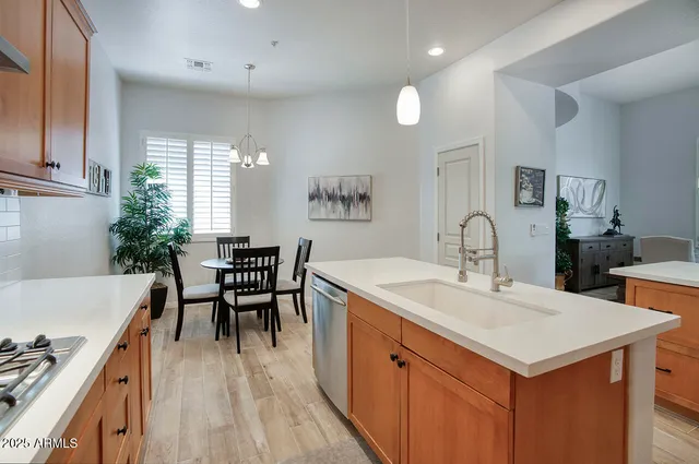 a dining hall with stainless steel appliances granite countertop a kitchen island a stove a sink a dining table and chairs with wooden floor