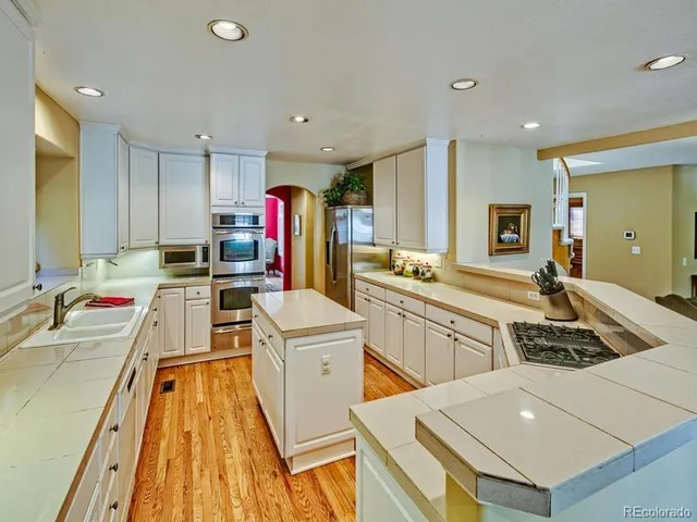 a kitchen that has a lot of white cabinets and stainless steel appliances