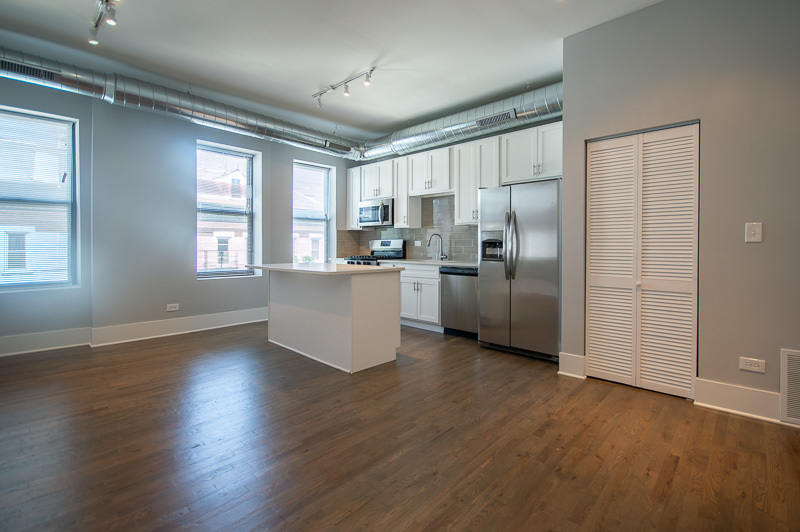 1044 West 18th Street, Unit 3M Chicago, IL 60608 - Photo 2 of 8 a kitchen with stainless steel appliances wooden floor and a window