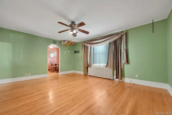 a view of an empty room with a window and wooden floor