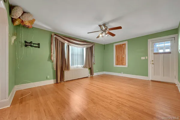 a view of an empty room with window and wooden floor