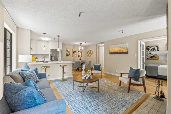 a living room with stainless steel appliances kitchen island granite countertop furniture and rug