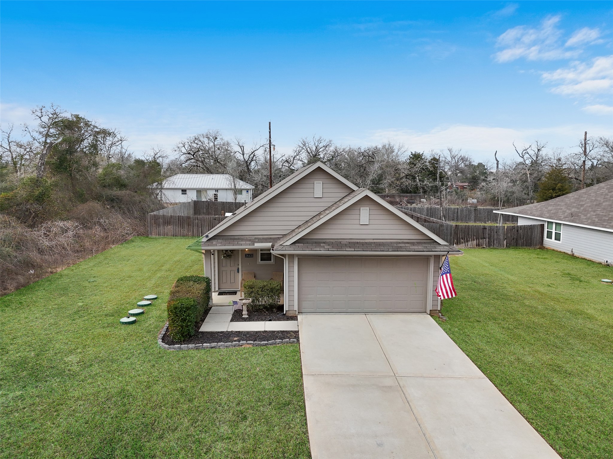 26431 Pin Oak Drive Hempstead, TX 77445 - Photo 25 of 32 Front exterior view with attached 2-car garage, extended driveway, and a wide, open front lawn. Lawn appearance has been digitally enhanced.