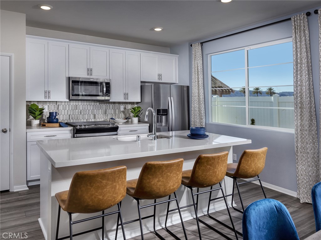 2147 Bergamot Street Redlands, CA 92374 - Photo 2 of 20 a kitchen with stainless steel appliances granite countertop a stove a refrigerator a kitchen island and chairs in it