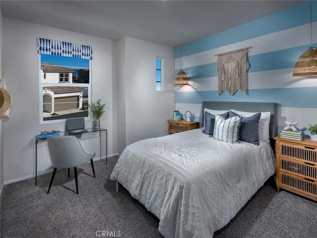 a bedroom with a bed a chair and potted plant on the dresser