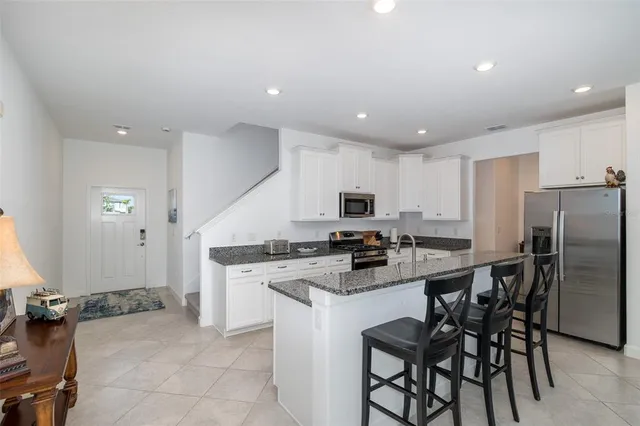 a kitchen with stainless steel appliances granite countertop a table chairs sink and cabinets