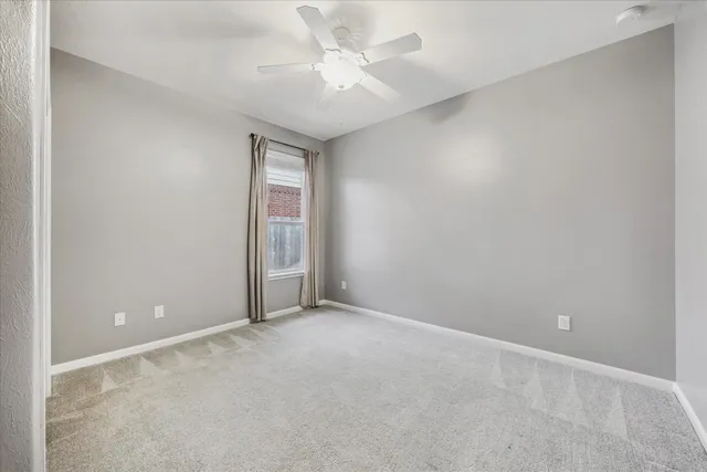 an empty room with a ceiling fan and a window