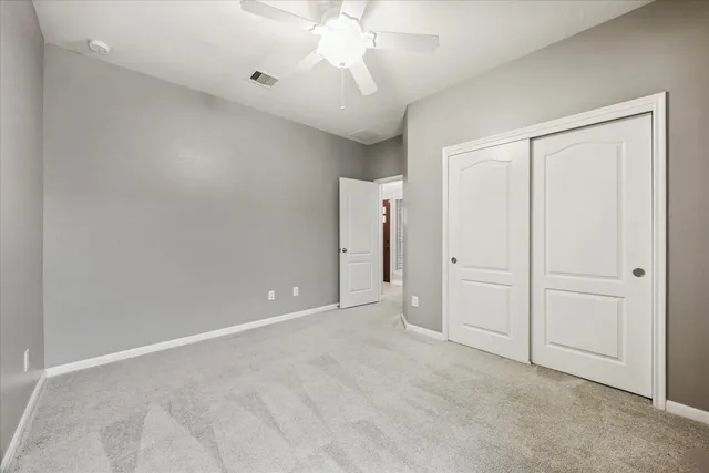 an empty room with chandelier fan and closet area