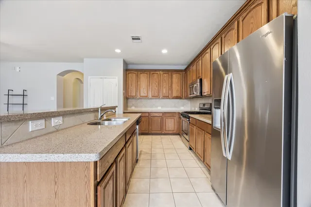 a kitchen with granite countertop a refrigerator a sink a stove a microwave and island